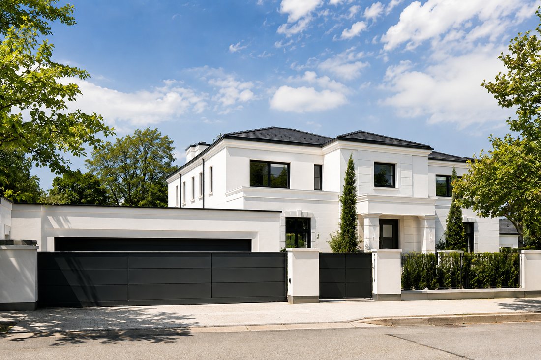 Fertiggestellte Villa mit weißer Putzfassade und dunklem Einfahrtstor